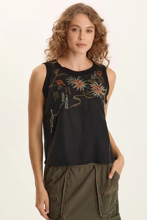 Woman wearing a black sleeveless top with floral designs on a beige background