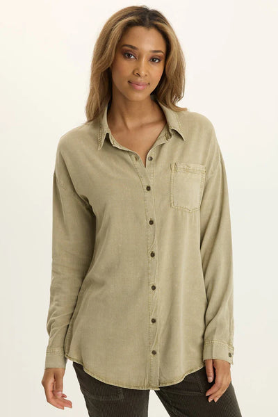 Woman wearing a light brown button-up shirt on a white background