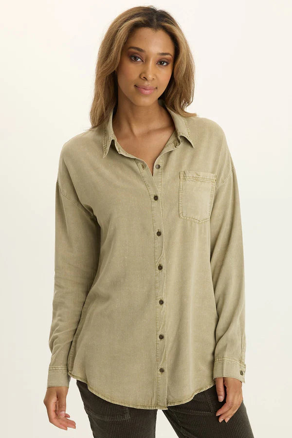 Woman wearing a light brown button-up shirt on a white background