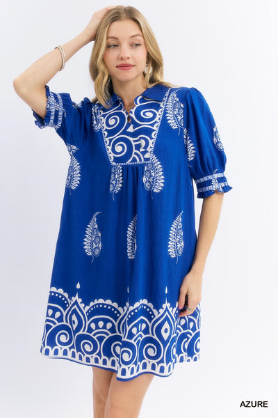 Woman wearing a blue dress with white patterns on a white background