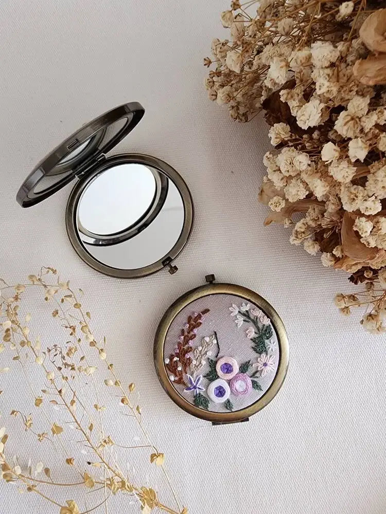 Compact mirror with floral design on a light background with dried flowers